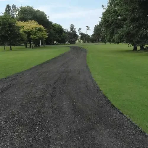A freshly compacted crushed asphalt driveway at a Charlotte residential property, showing a dark, firm surface with clean edges. The millings are evenly spread and rolled flat, giving the driveway a pavement-like appearance.